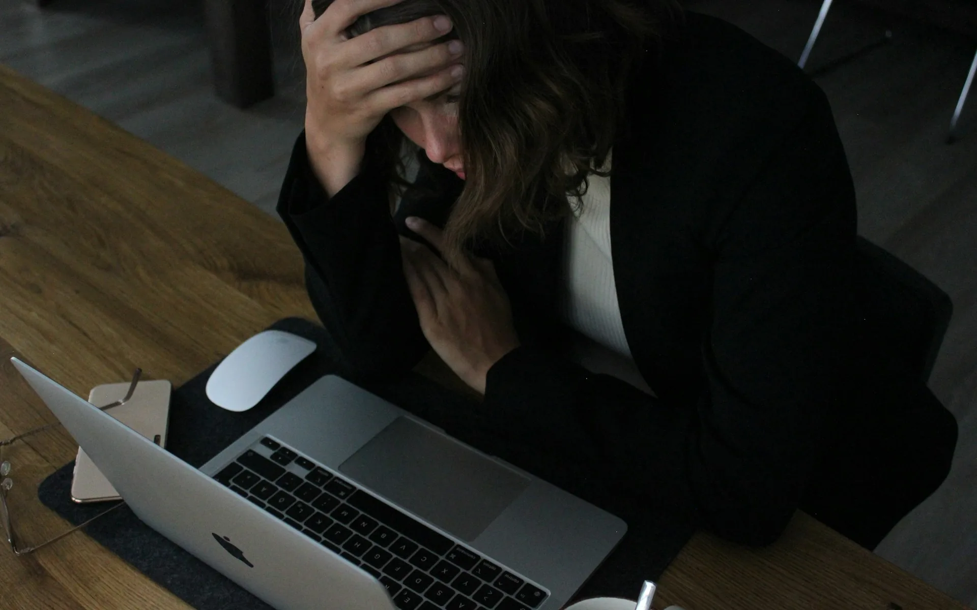 A stressed person with their head in their hands at a laptop, representing the business cost of slow websites